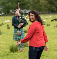 Woman traveler with bagpiper, Scotland