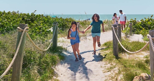 Family walking on a beach path near the ocean.