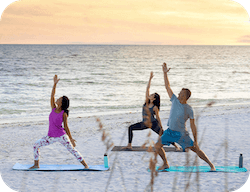 A group practicing yoga on a beach.