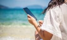 woman holding cell phone on beach